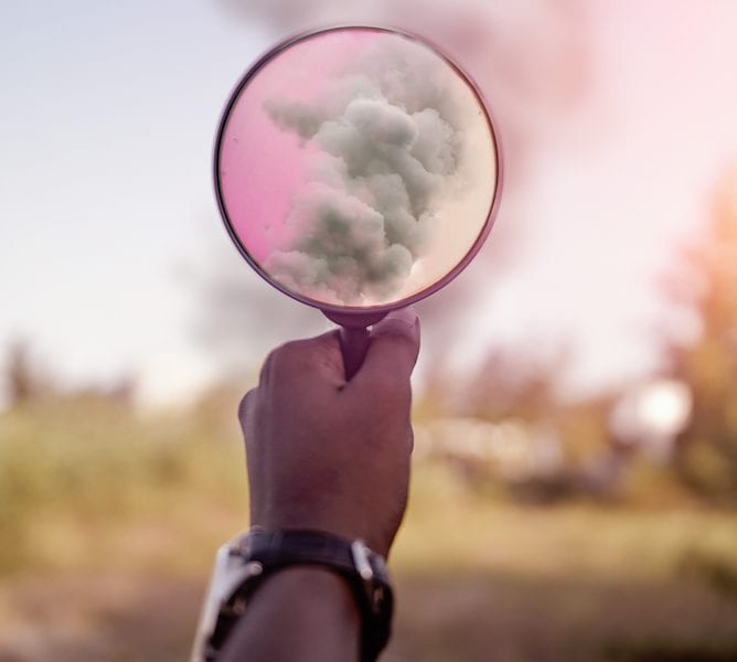 hand holding a magnifying glass with smoke