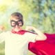 superhero kid with arms up in a flexing muscle position and cape