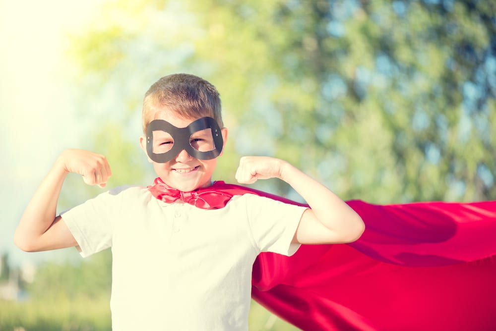 superhero kid with arms up in a flexing muscle position and cape