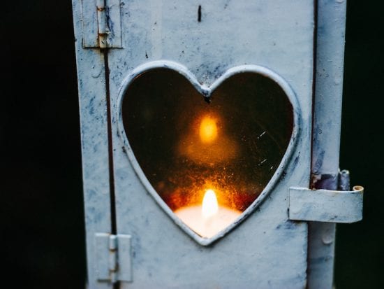 candle burning in a heart shaped window