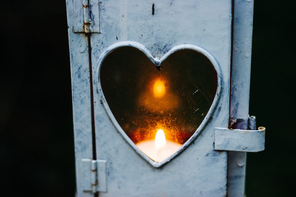 candle burning in a heart shaped window