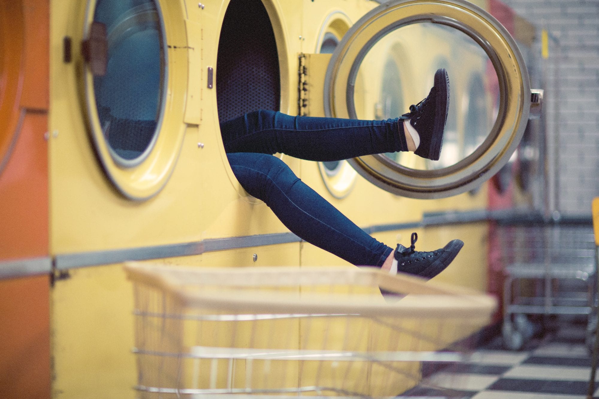 woman's legs sticking out of a dryer at the laundromat