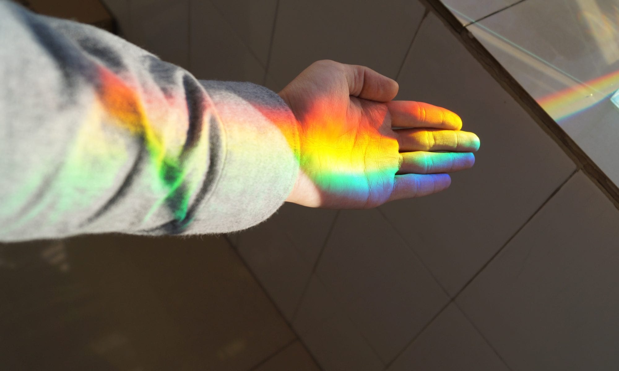 open palm with a rainbow shining across