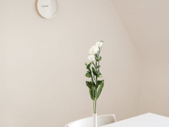 white flowers on a table in a white room with a clock