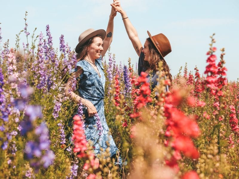two women high fiving in a field of flowers