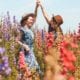 two women high fiving in a field of flowers