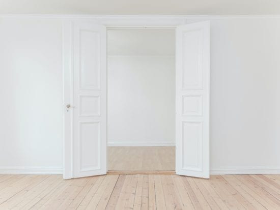 a set of double doors opening to an empty white room